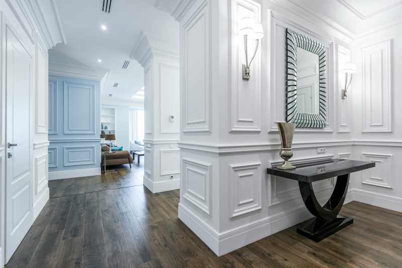 Interior of a home with classical white walls and wood floor, featuring LED lighting sconces on either side of a mirror - Shop C2CLights.com.